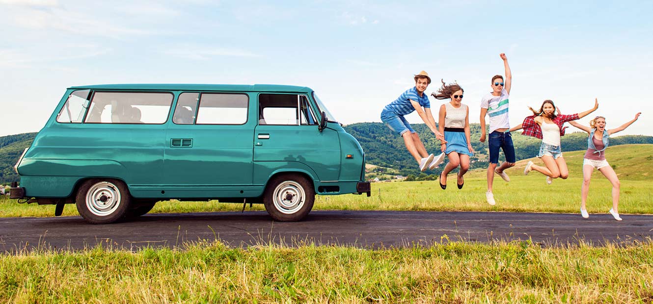 Young friends jumping for joy in front of their van.