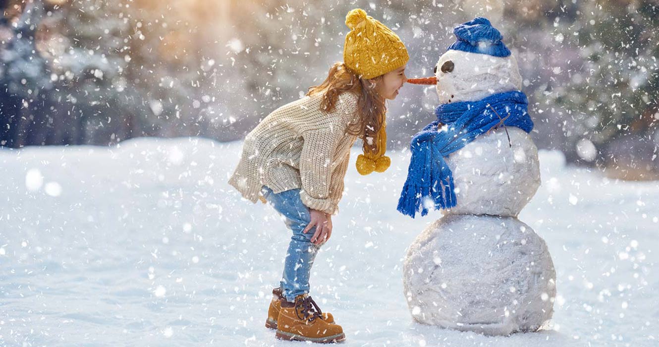 Child playing with snowman